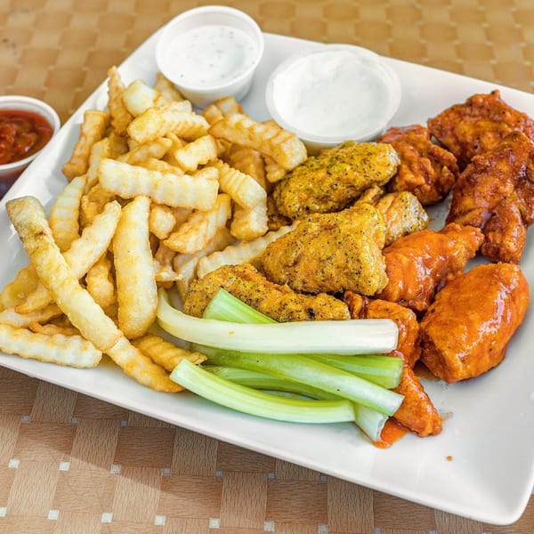 A plate of Lokman's Best Wings with fries, celery sticks, ketchup, and two dipping sauces.