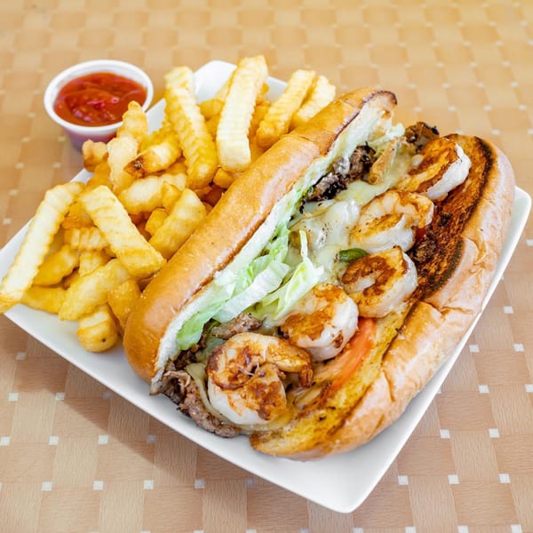 A Lokman's Best Wings cheesesteak with shrimp, lettuce, and tomatoes, served with crinkle-cut fries and ketchup.