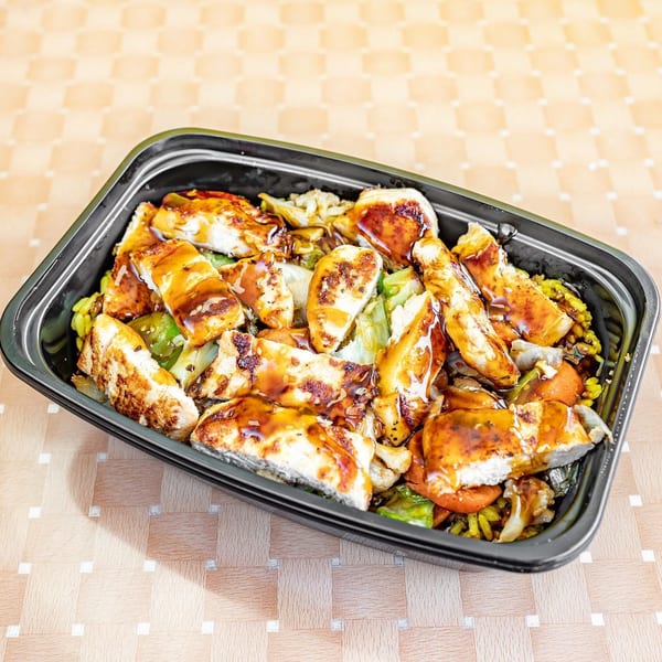Grilled chicken strips with sauce, vegetables, and rice in a black takeout container.